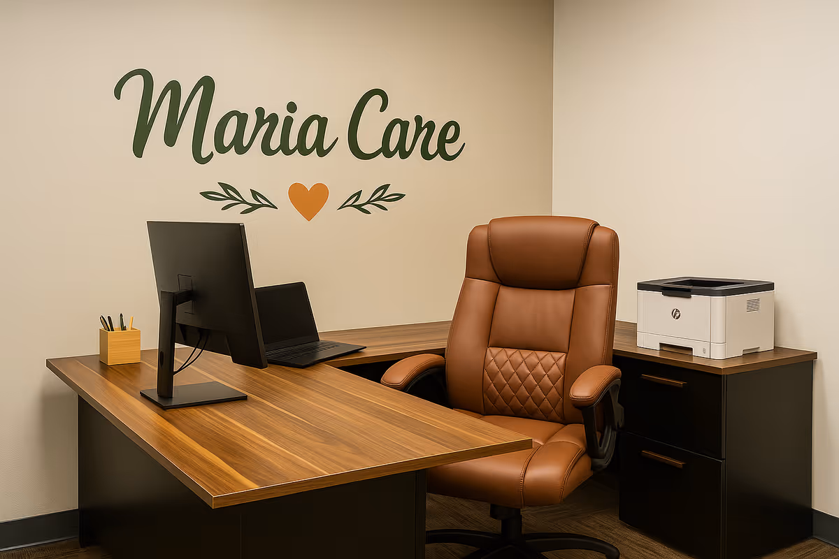 Maria Care reception desk with computer, leather chair, and printer in an office space.
