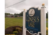 Front sign for Conesus Lake Nursing Home with lawn and a distant building