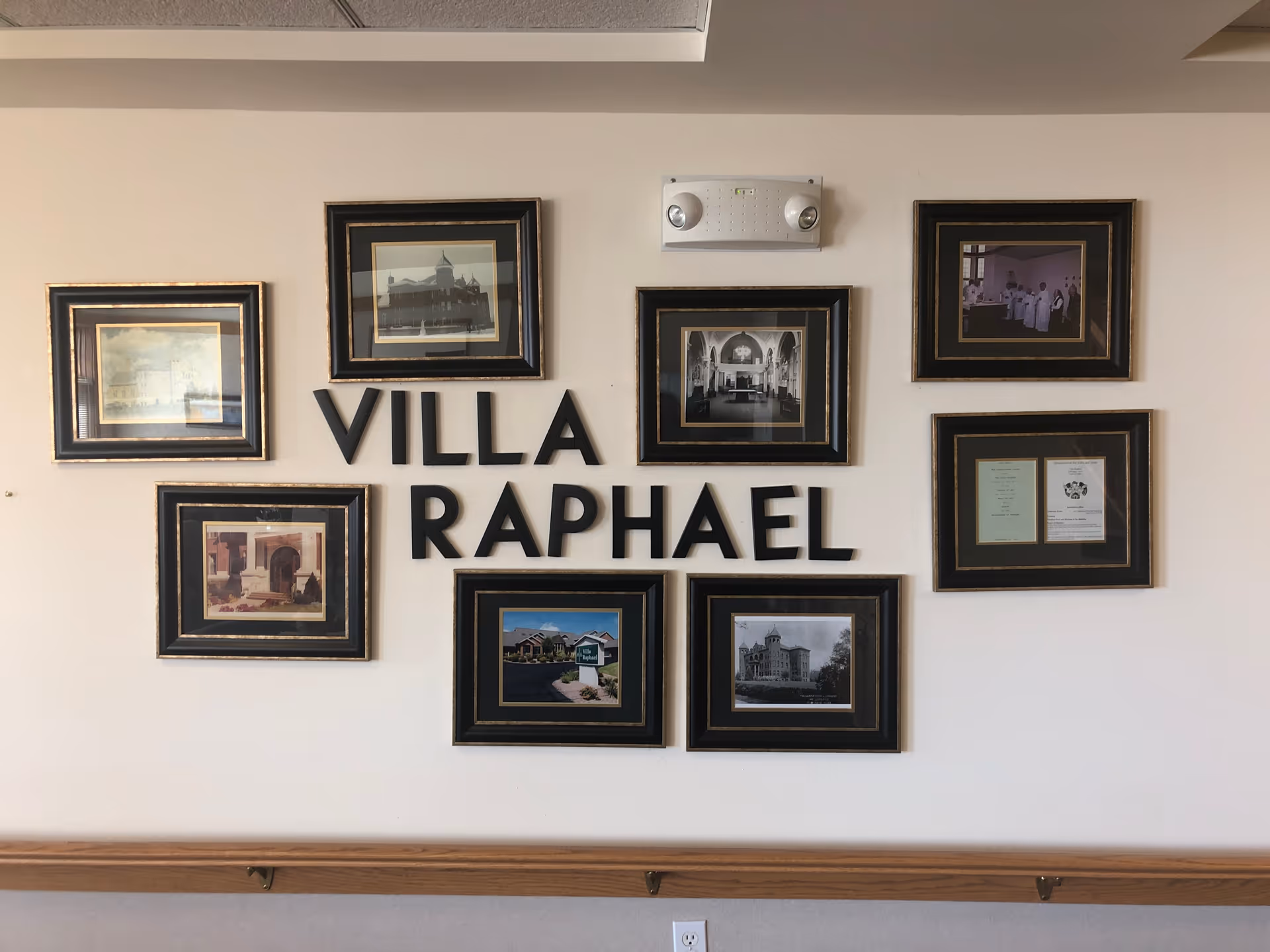 Wall display with several framed photos and the words Villa Raphael indoors.