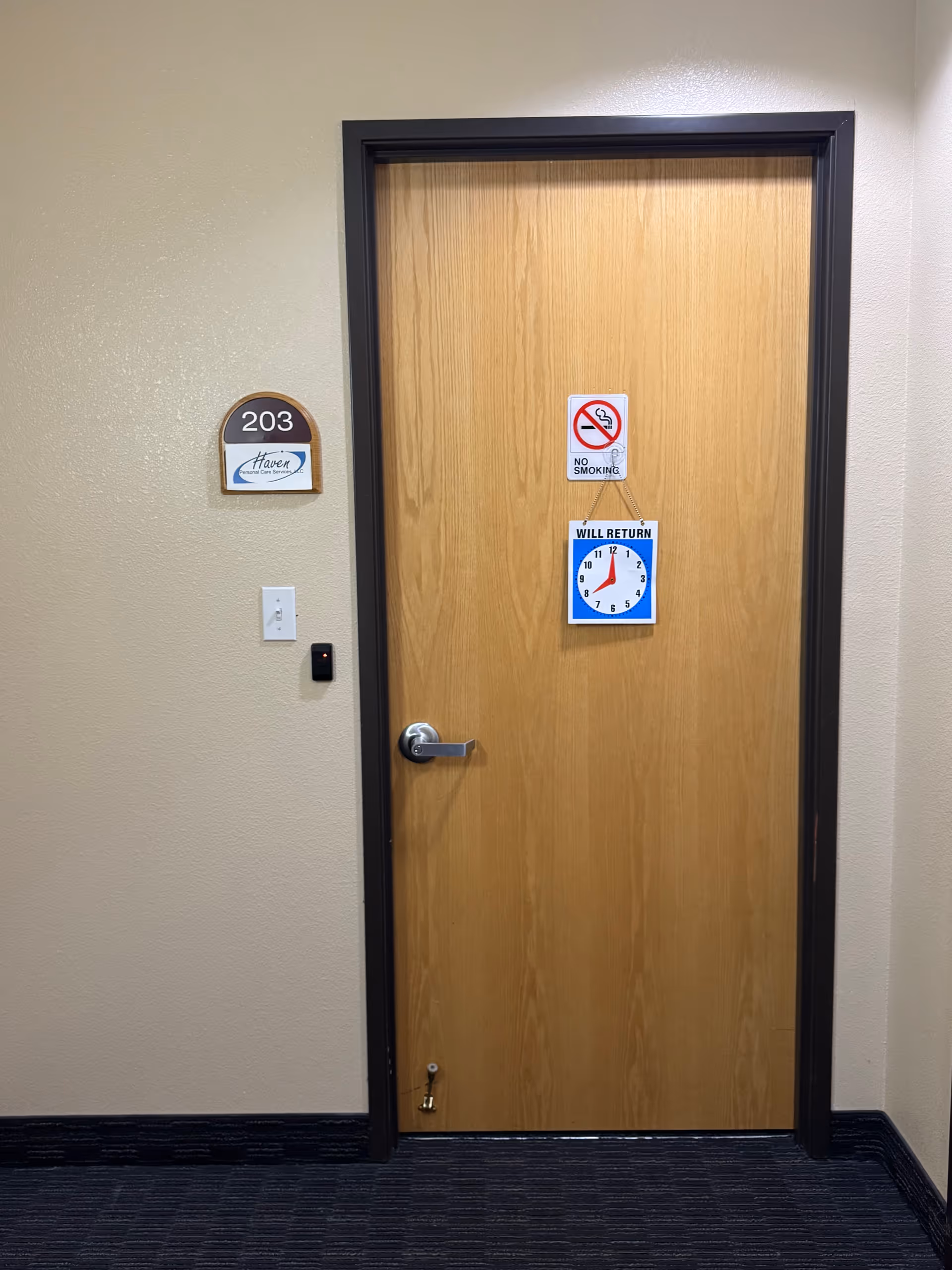 Wooden interior door in hallway with room number 203 and posted signs.