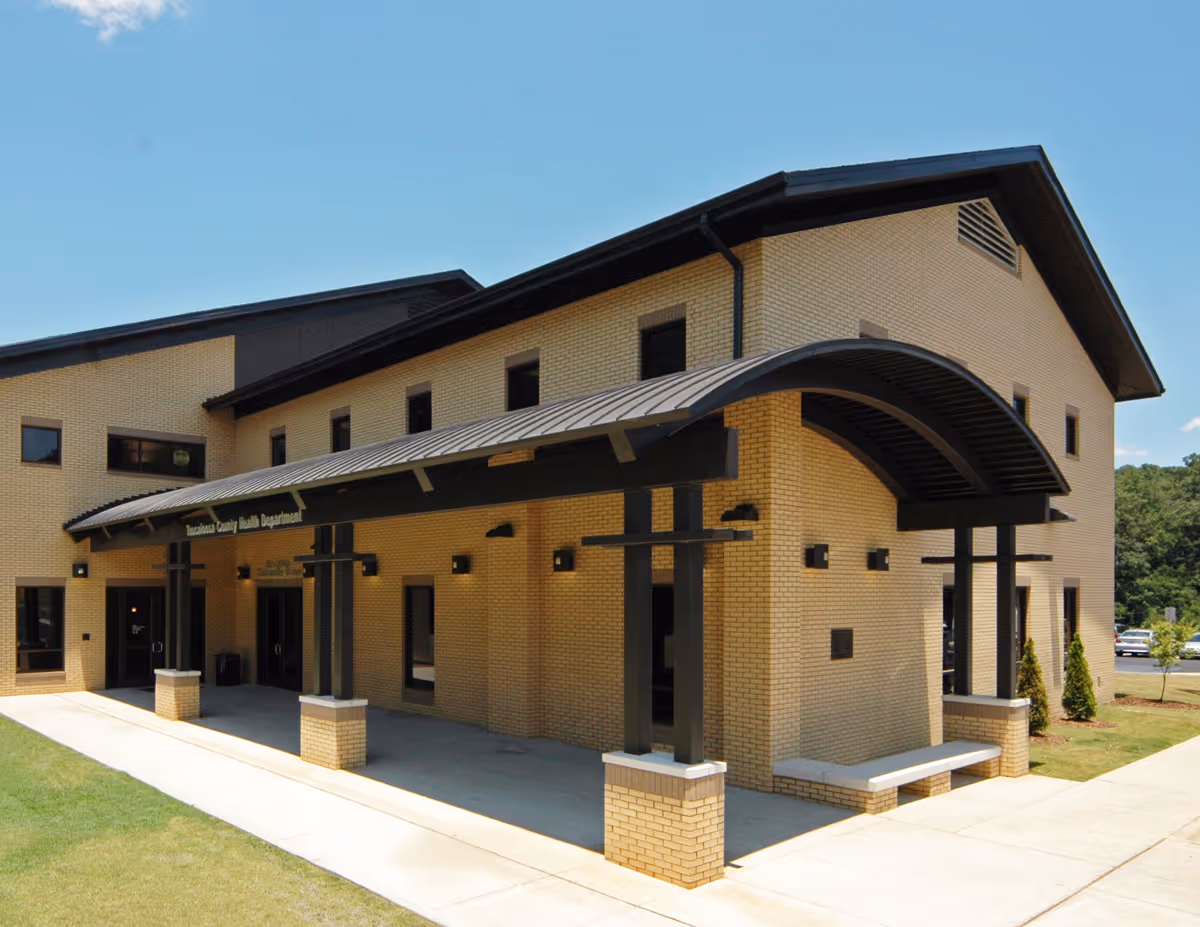 Exterior view of a brick health department building with a curved metal entrance awning.