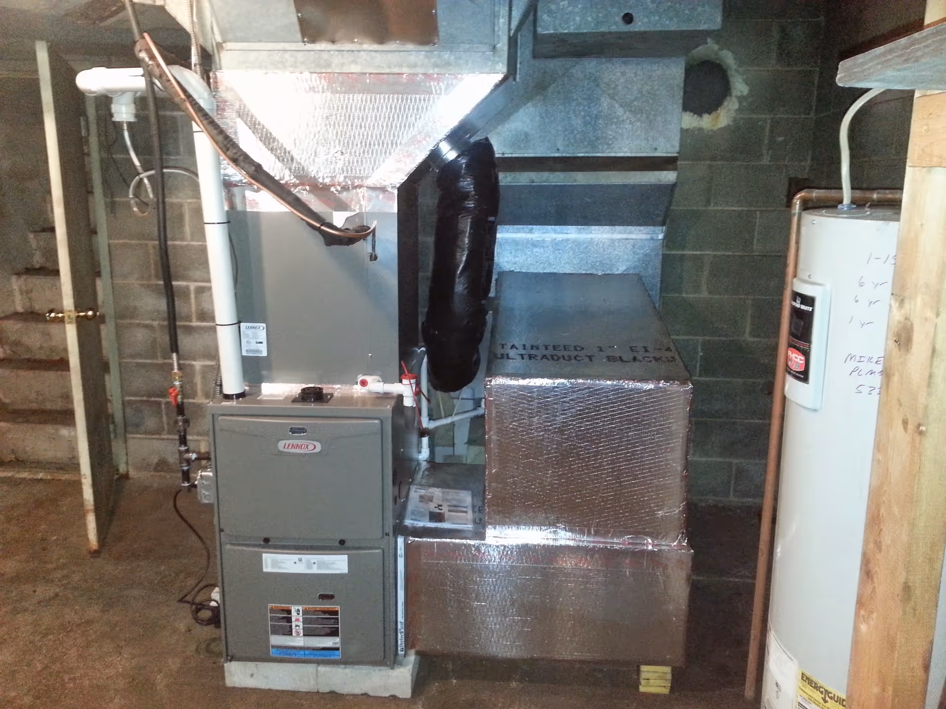 Basement utility room housing furnace, ductwork, and a water heater.