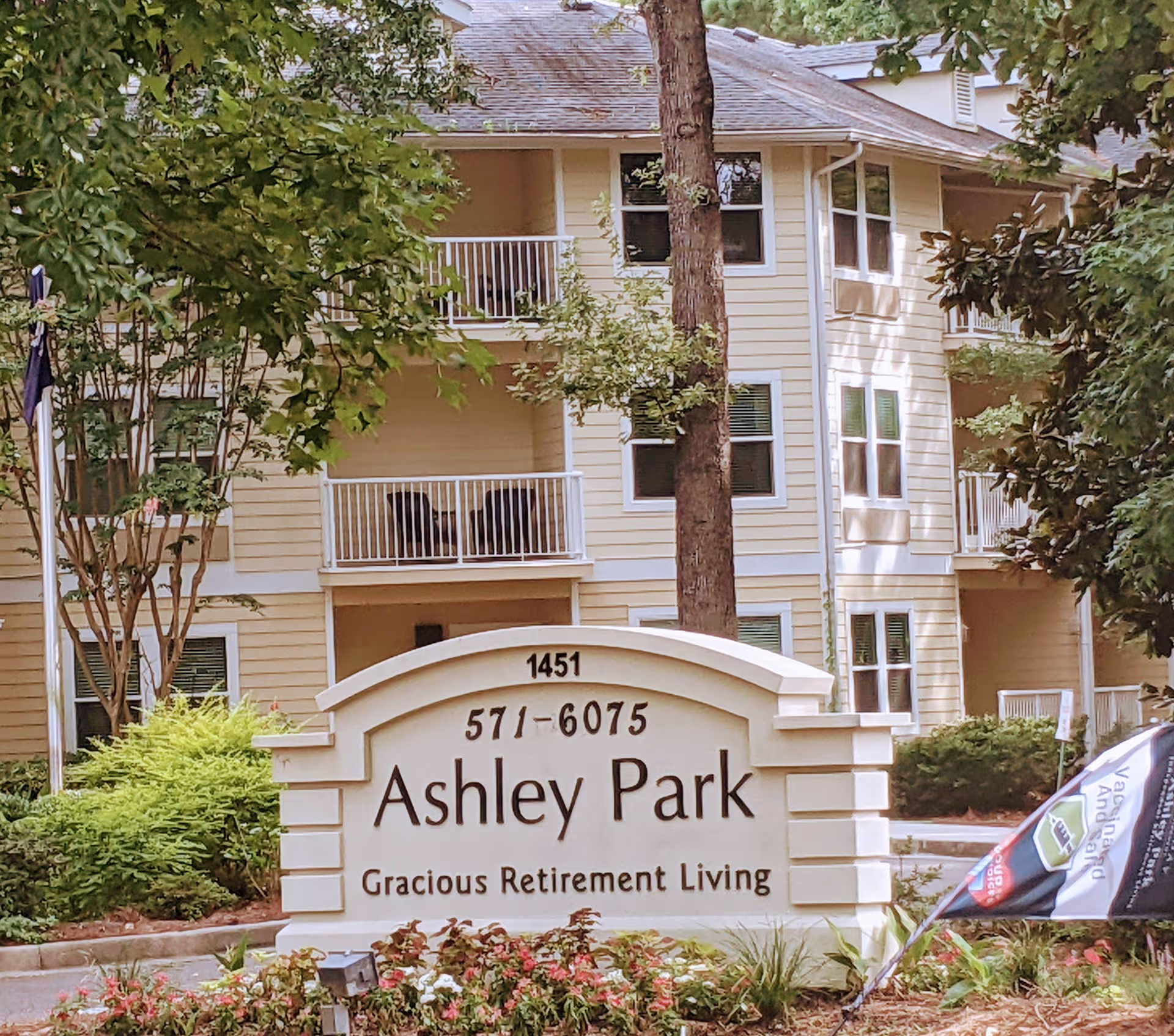 Two-story beige senior living building with balconies and a front sign reading Ashley Park.