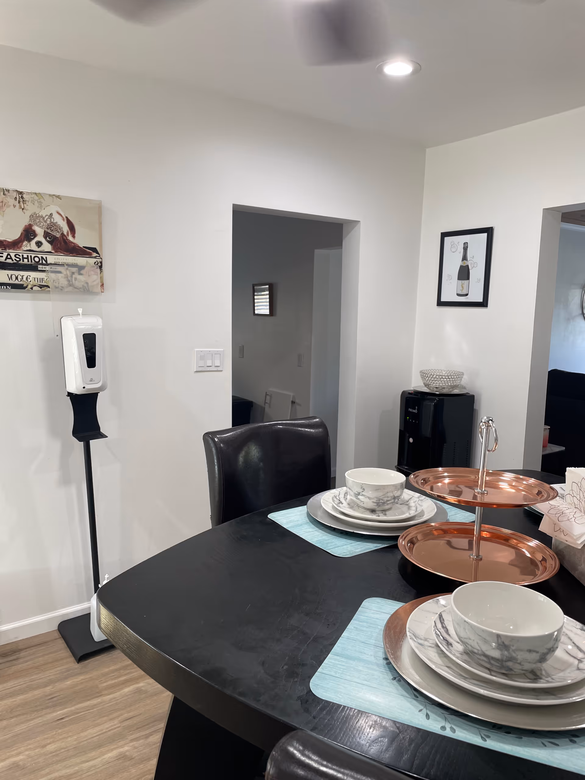 Dining table with plates, bowls, and a copper tiered serving stand in a bright dining area.