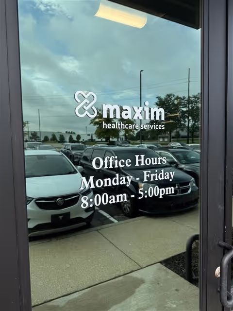 Glass entrance door displaying Maxim Healthcare Services logo and office hours.