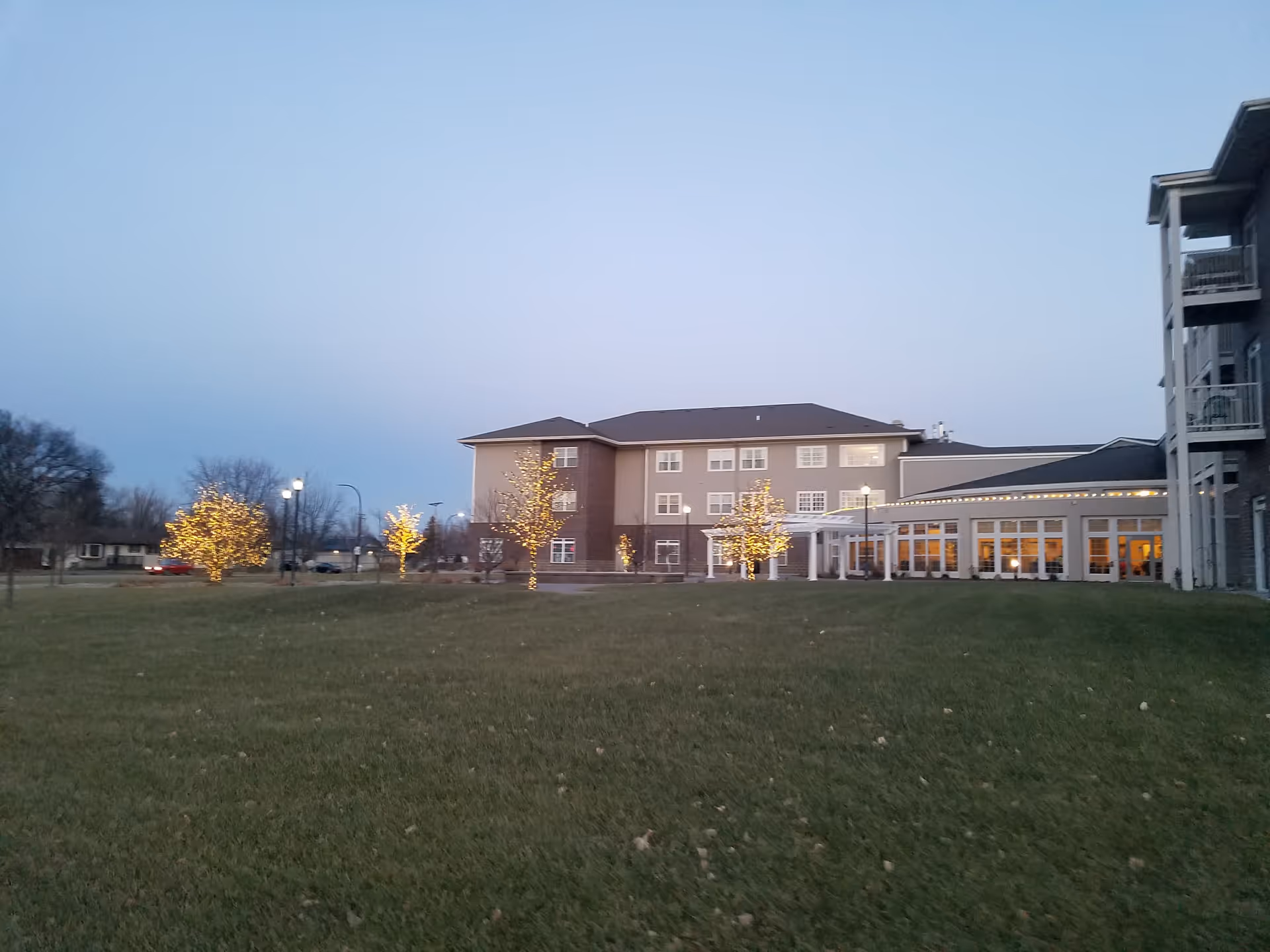 Exterior view of Eventide at Sheyenne Crossings with lit trees and lawn.