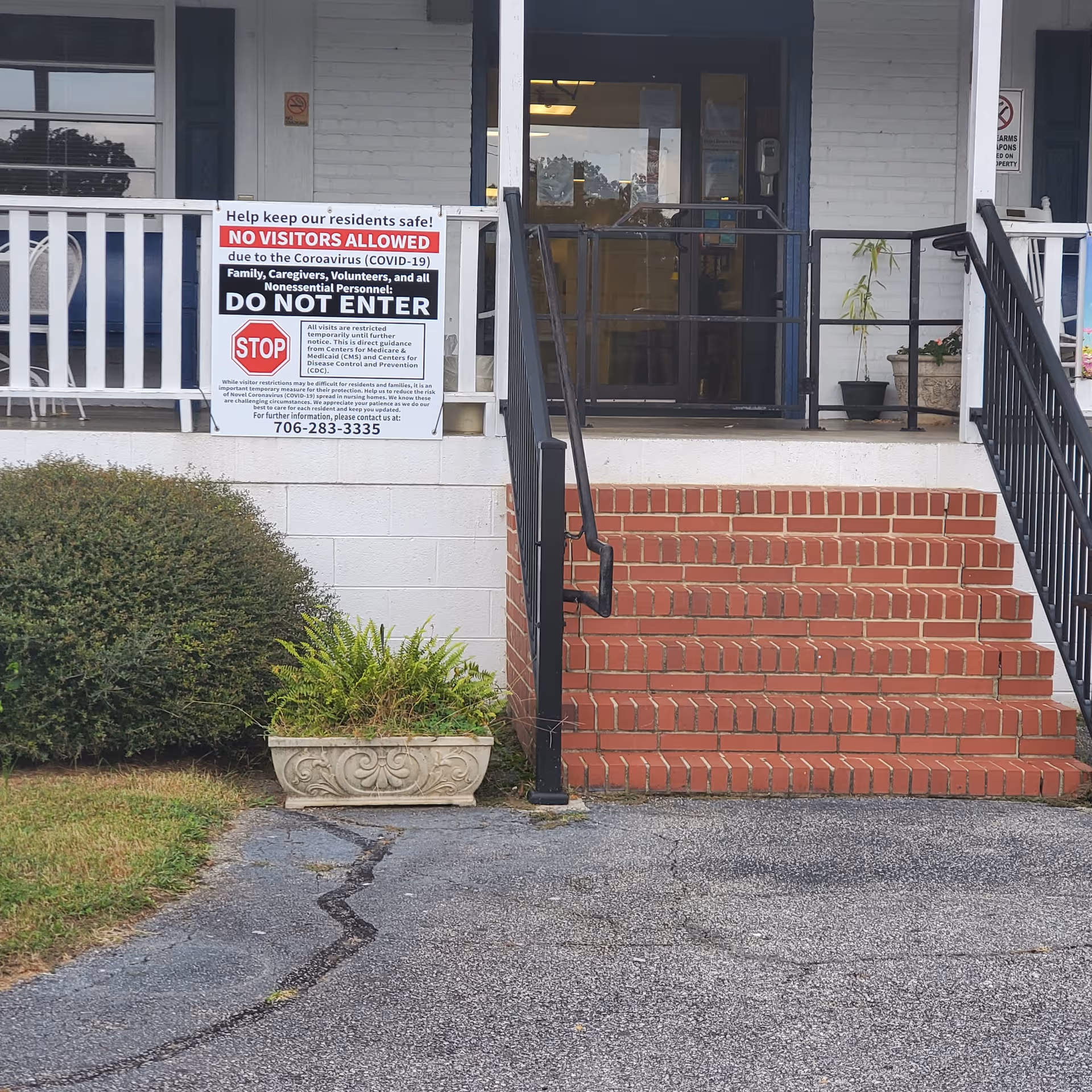 Front entrance of a nursing center with brick steps and a large visitor restriction sign.