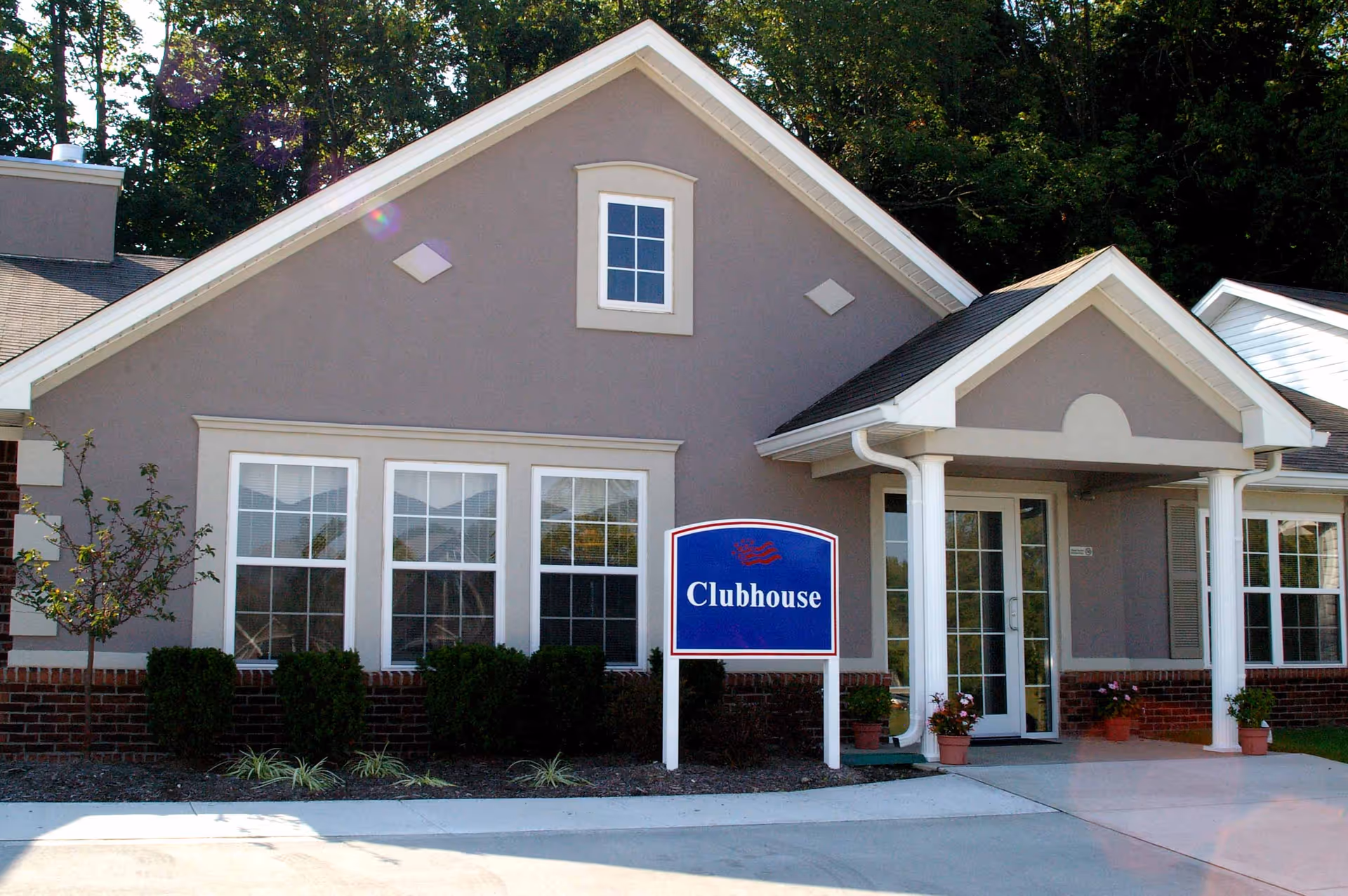 Front exterior of Meadow Lakes clubhouse with a blue Clubhouse sign