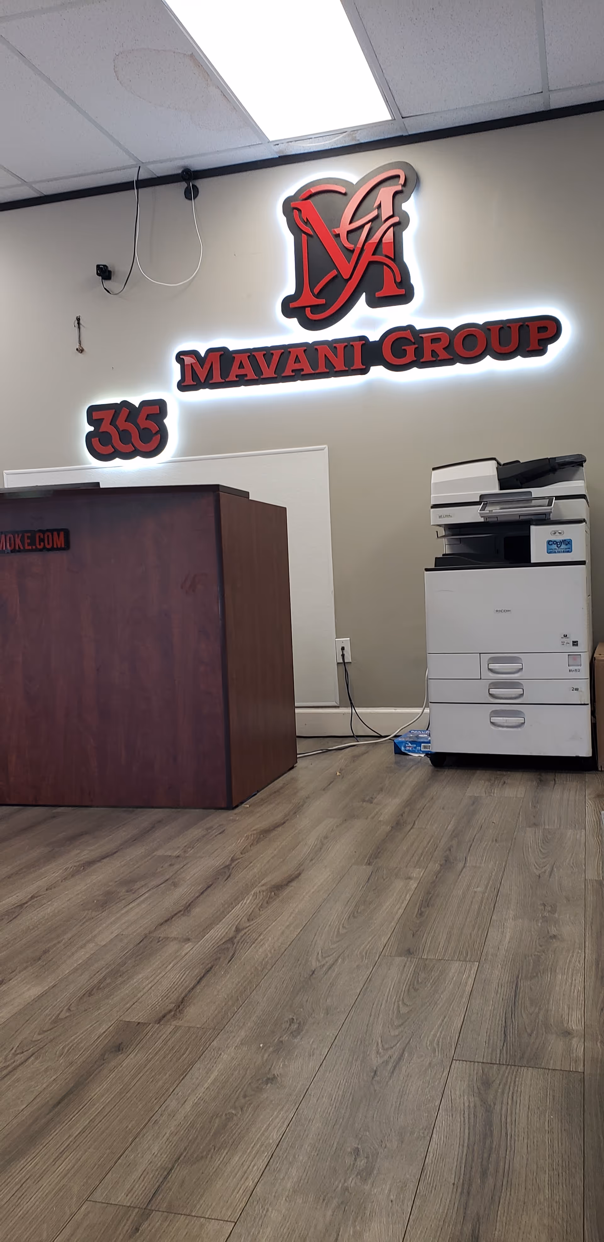 Lobby of JMM Home Health featuring a reception desk, copier, and illuminated company sign.