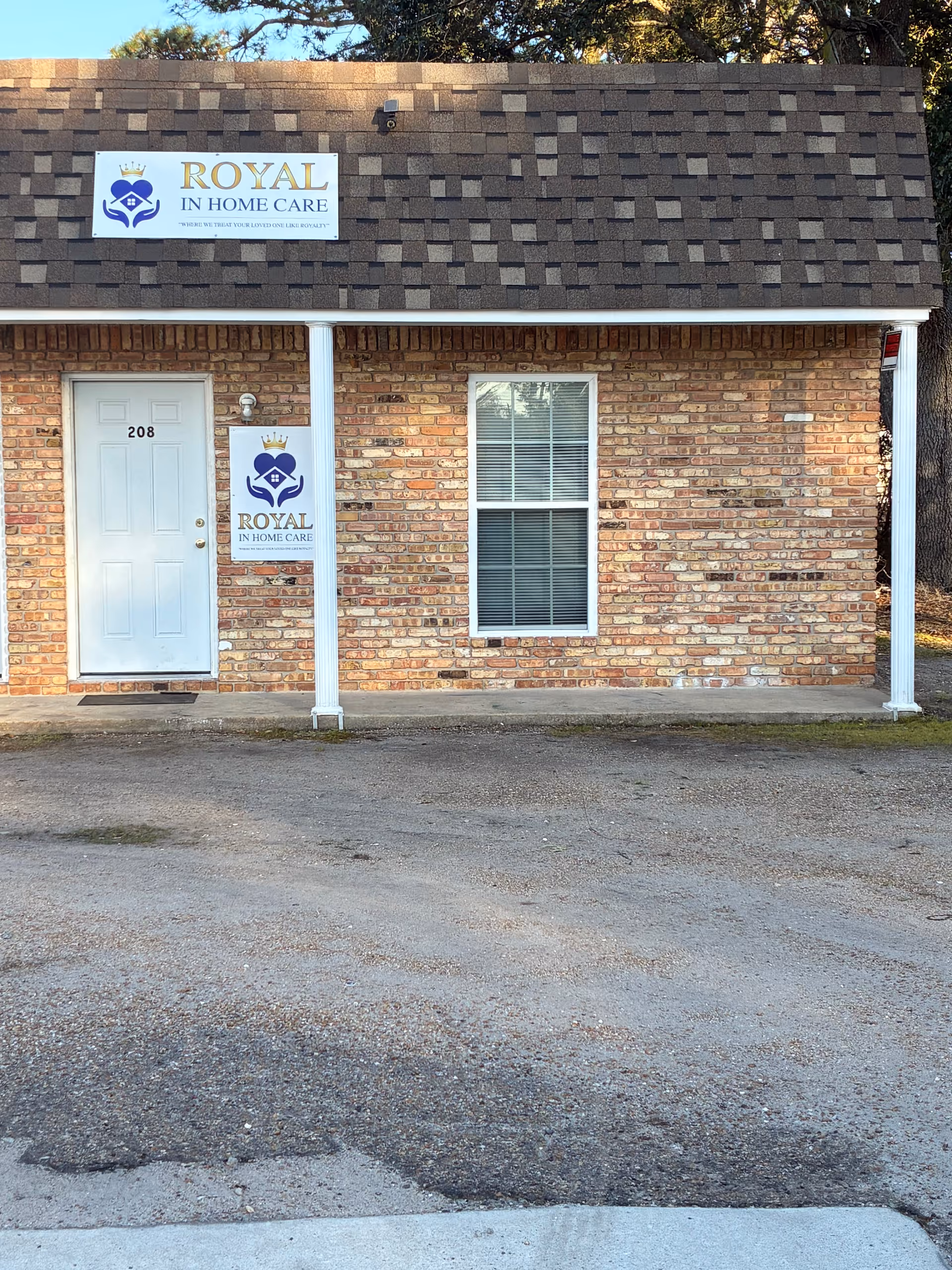Brick building front with Royal In Home Care sign, door labeled 208, window with blinds.