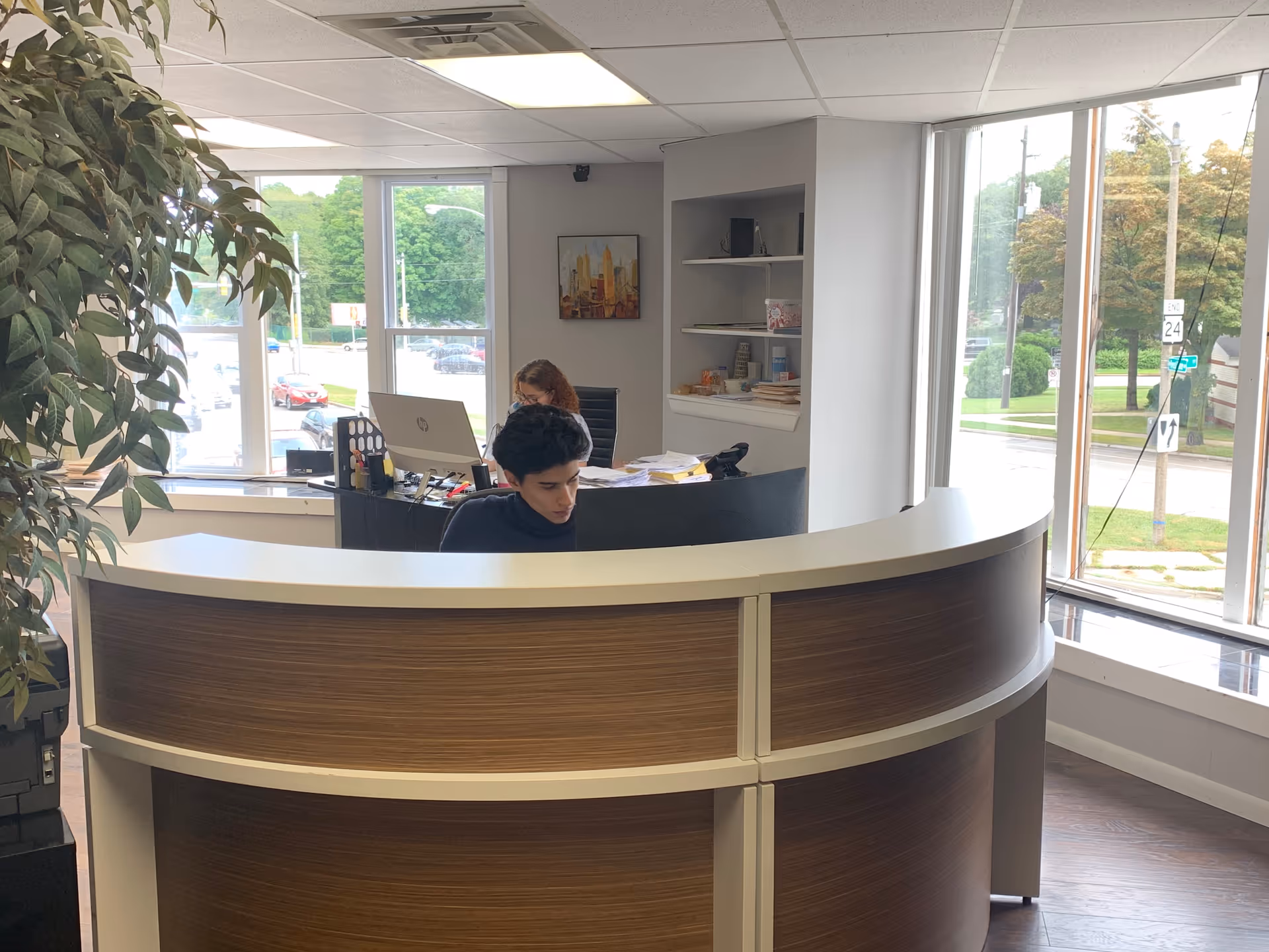 Two staff at a curved reception desk in a bright interior office.