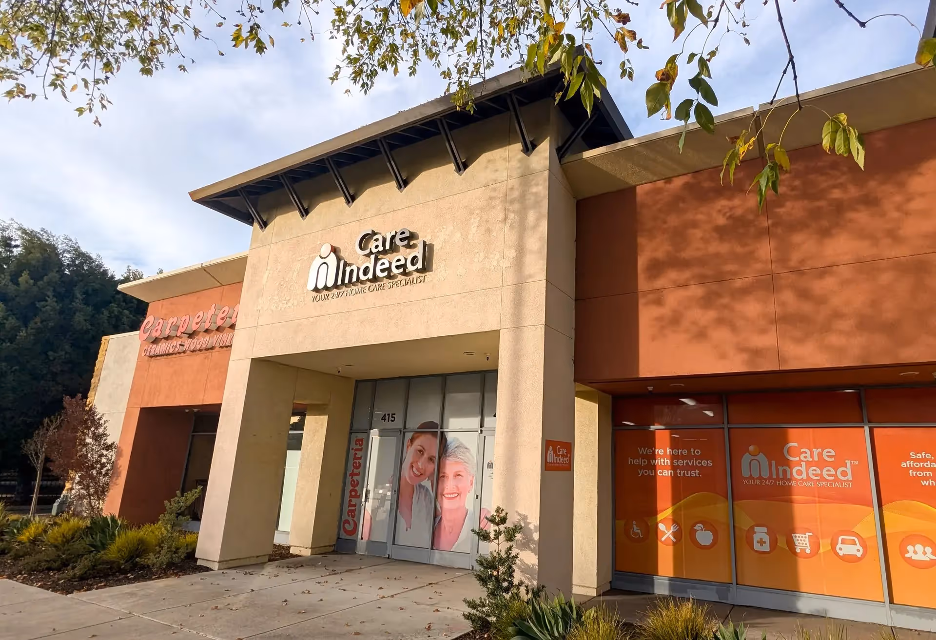 Exterior view of a Care Indeed facility with entrance doors and bright orange signage.