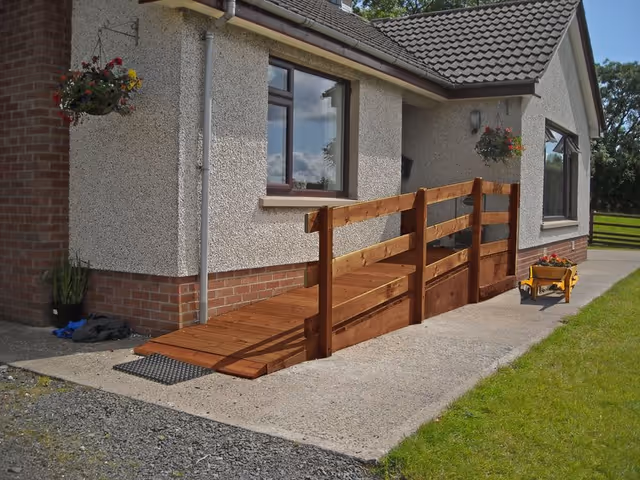 Exterior view of a building entrance with a wooden ramp and hanging baskets.