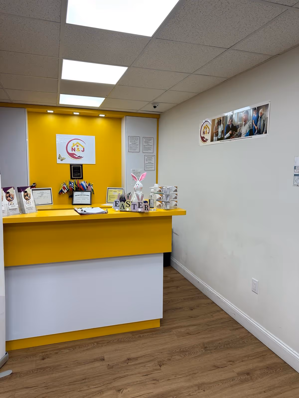 Bright yellow reception desk with N and J Home Care signage and Easter decorations.