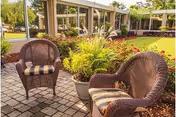 Outdoor seating area with wicker chairs and potted plants in a courtyard.