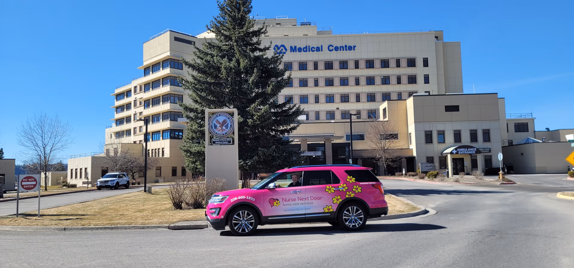 Front exterior of a medical center with a pink Nurse Next Door car in parking lot