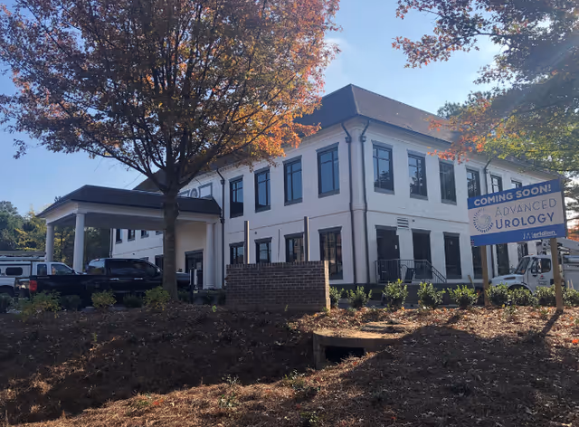 Two-story white building with a covered entrance and a 'Coming Soon' Advanced Urology sign.
