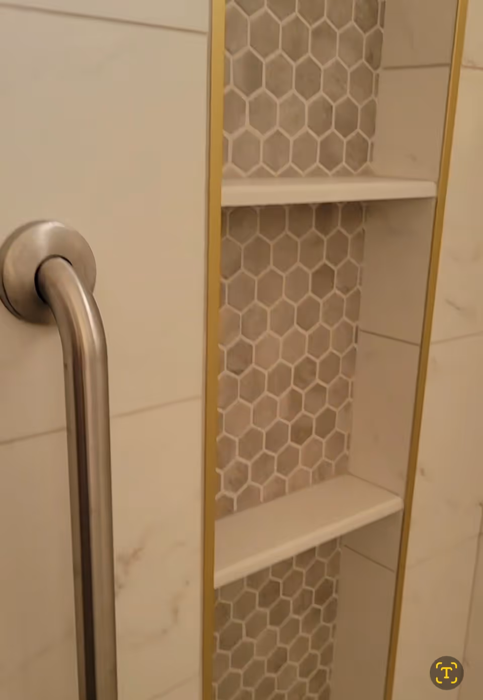 Shower niche with shelves and hexagonal tile insert in a bathroom.