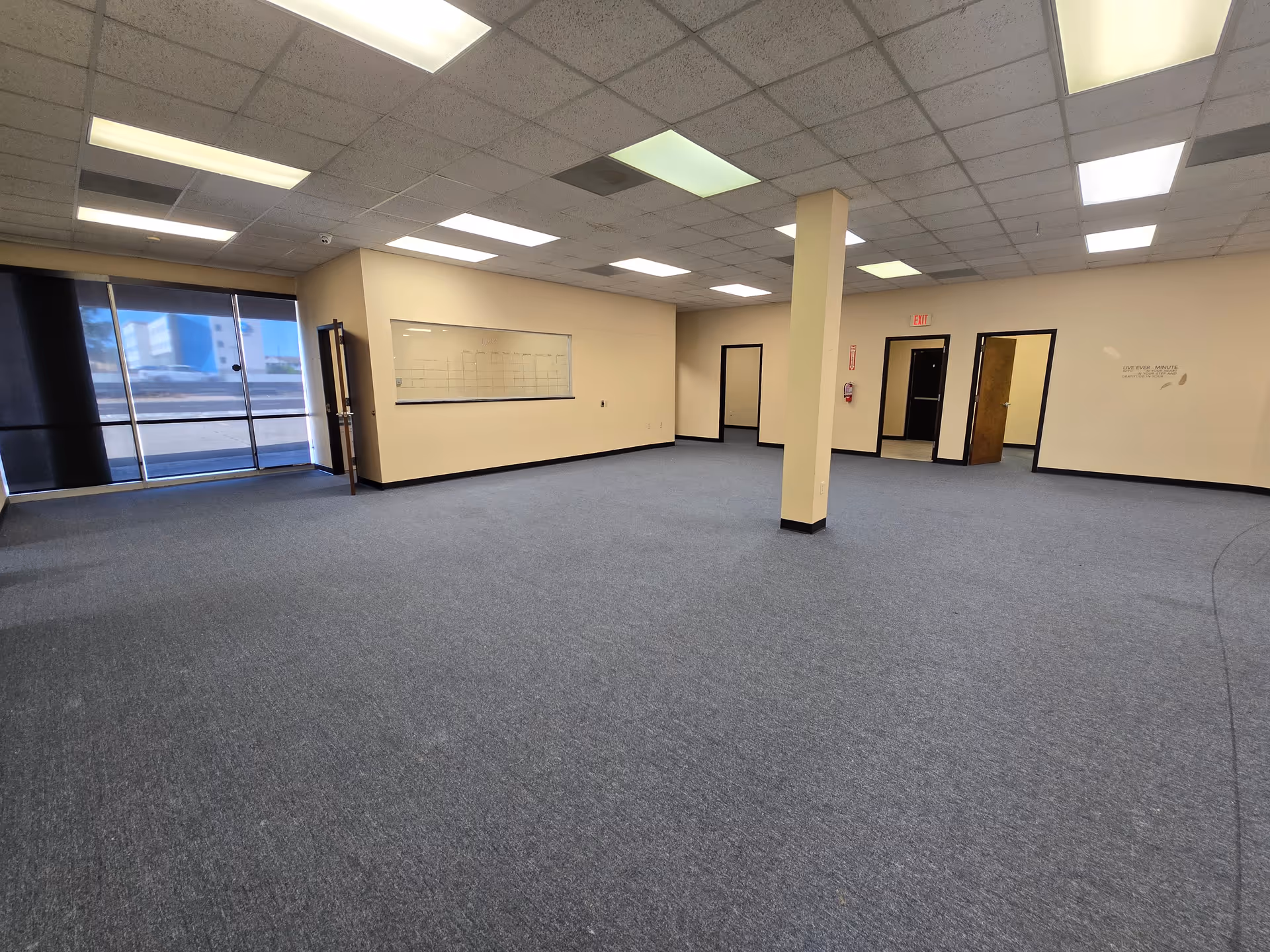 A spacious, empty interior room in Altus Hospice Corpus Christi with carpet and glass doors.