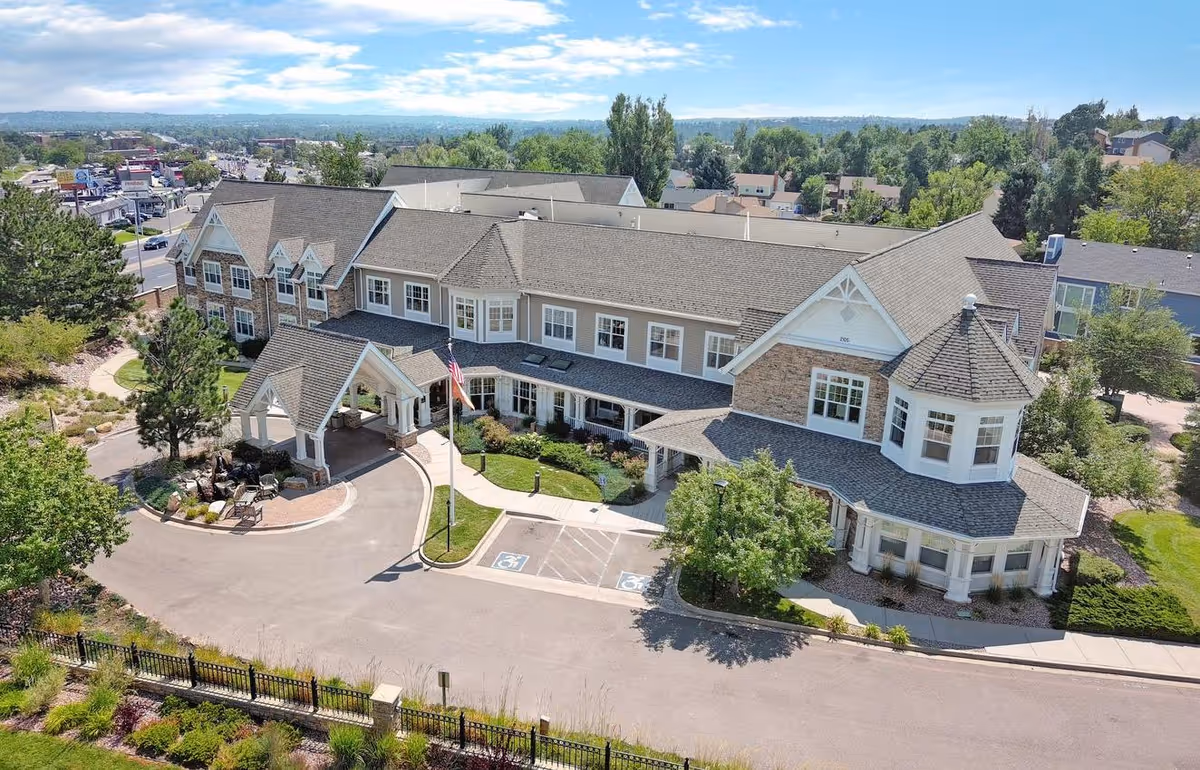 Aerial view of Hemsley House at University Park, a two-story senior living building with a covered entrance, parking spaces, and surrounding landscaping.