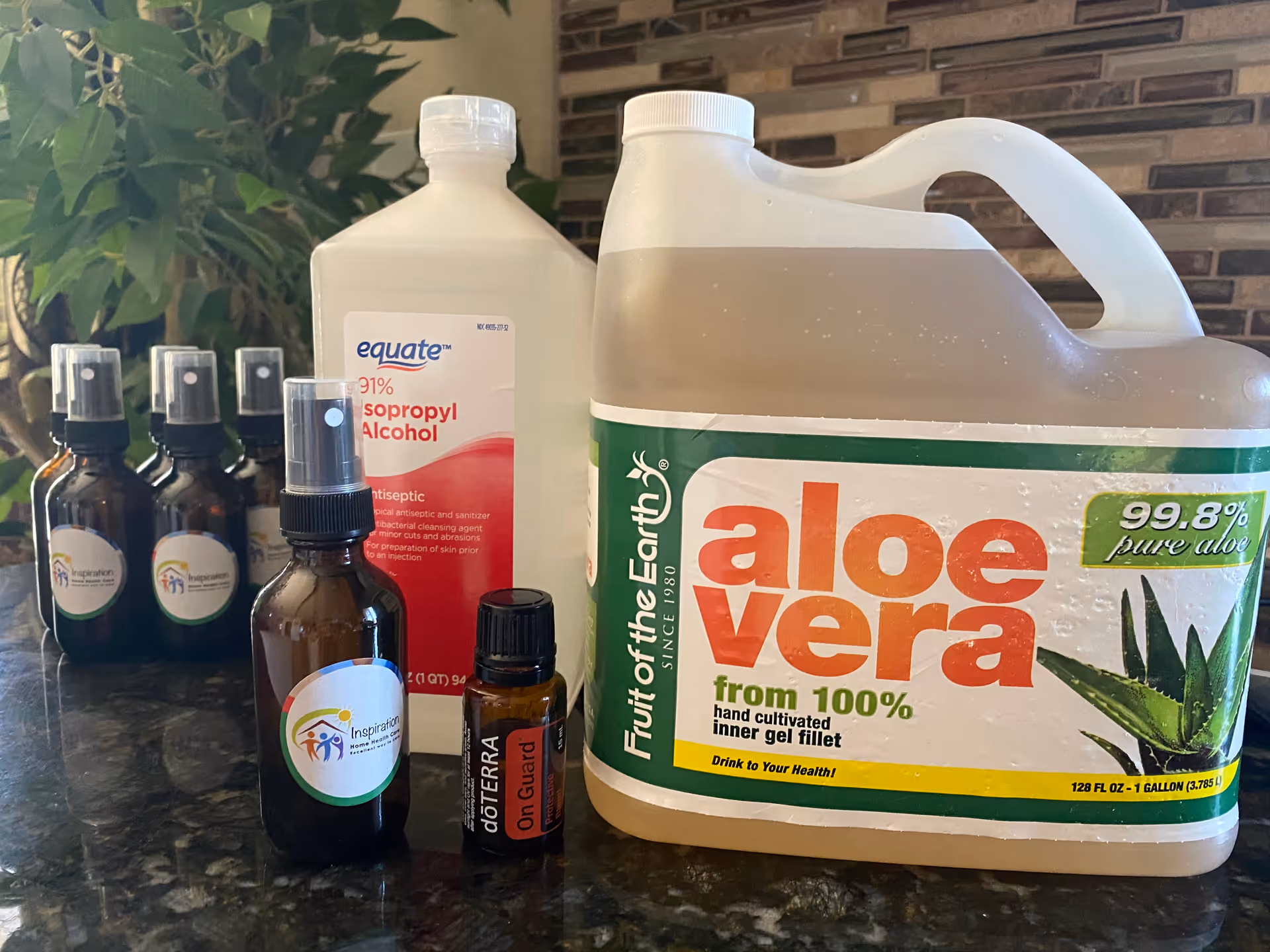 Assorted health care bottles and a large aloe vera container on a dark countertop.