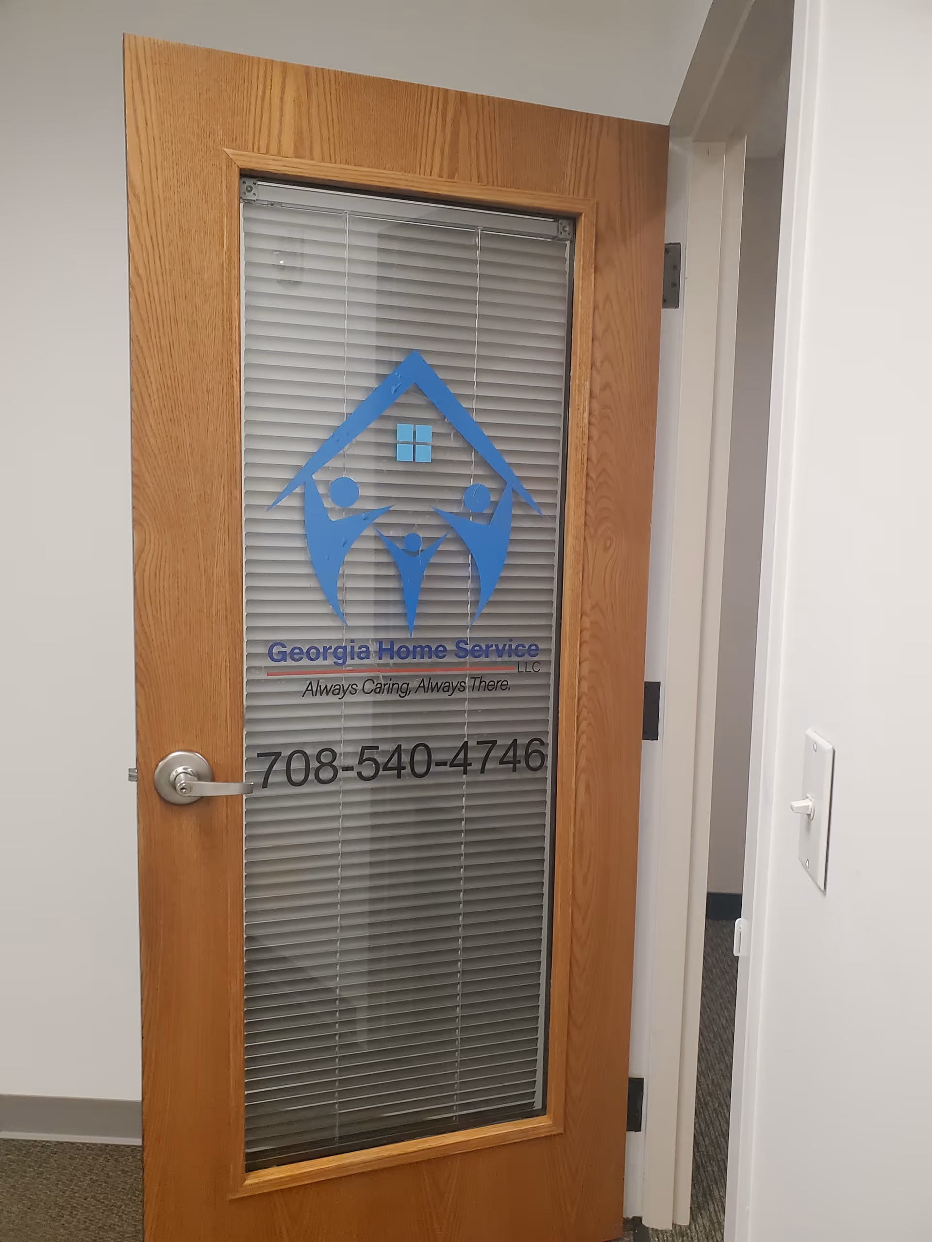 Wood-framed glass door with blinds displaying Georgia Home Service logo and phone number.