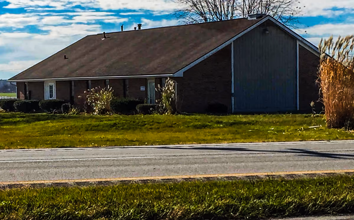 Front view of a single-story brick senior living facility beside a road.