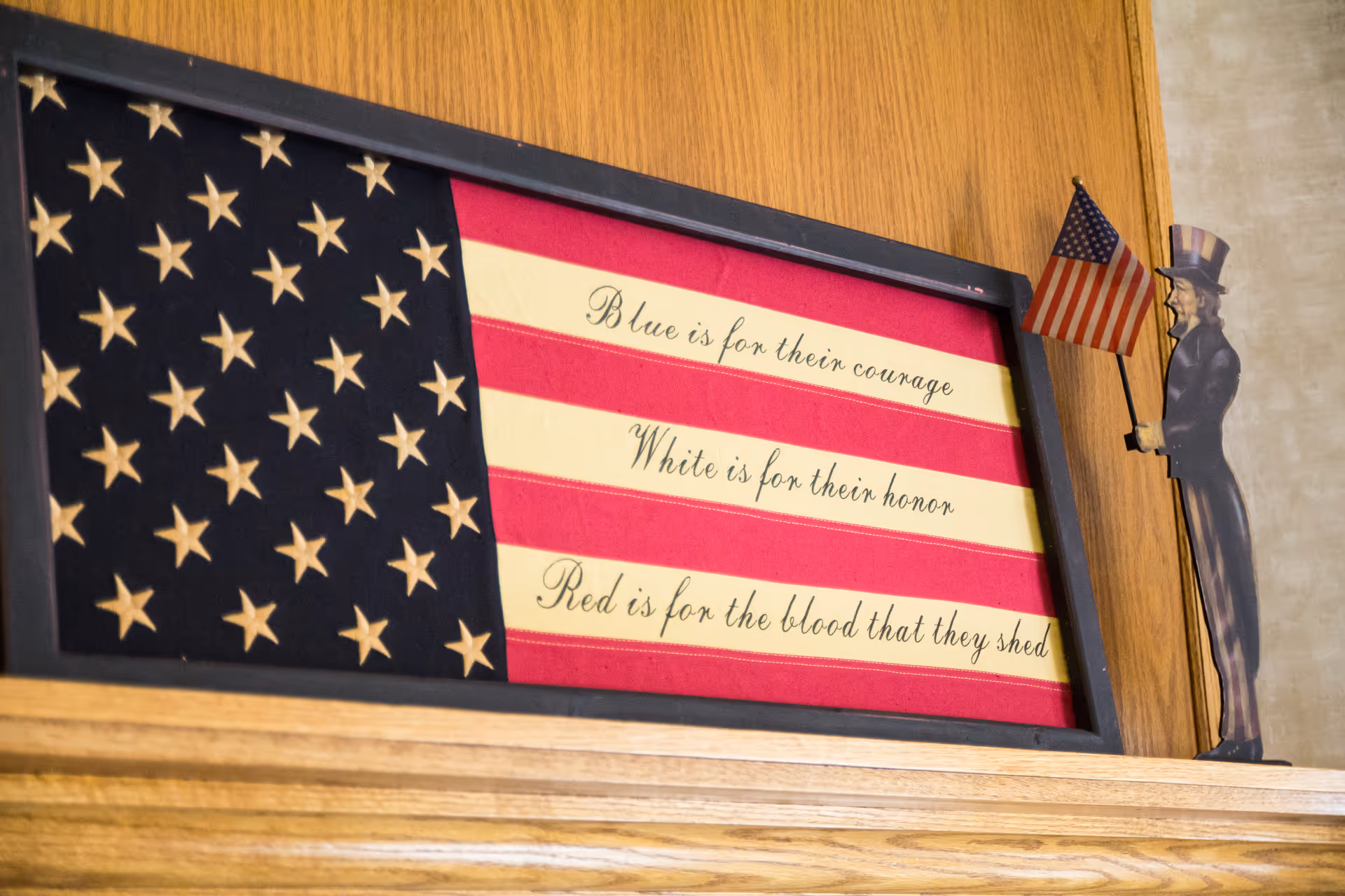 Patriotic framed flag display with a cutout figure indoors.