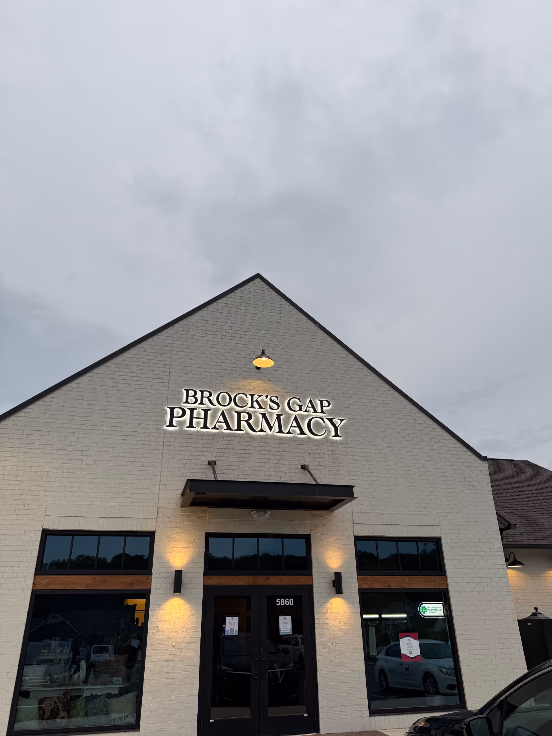 Front view of Brock's Gap Pharmacy storefront with glass doors and illuminated sign.