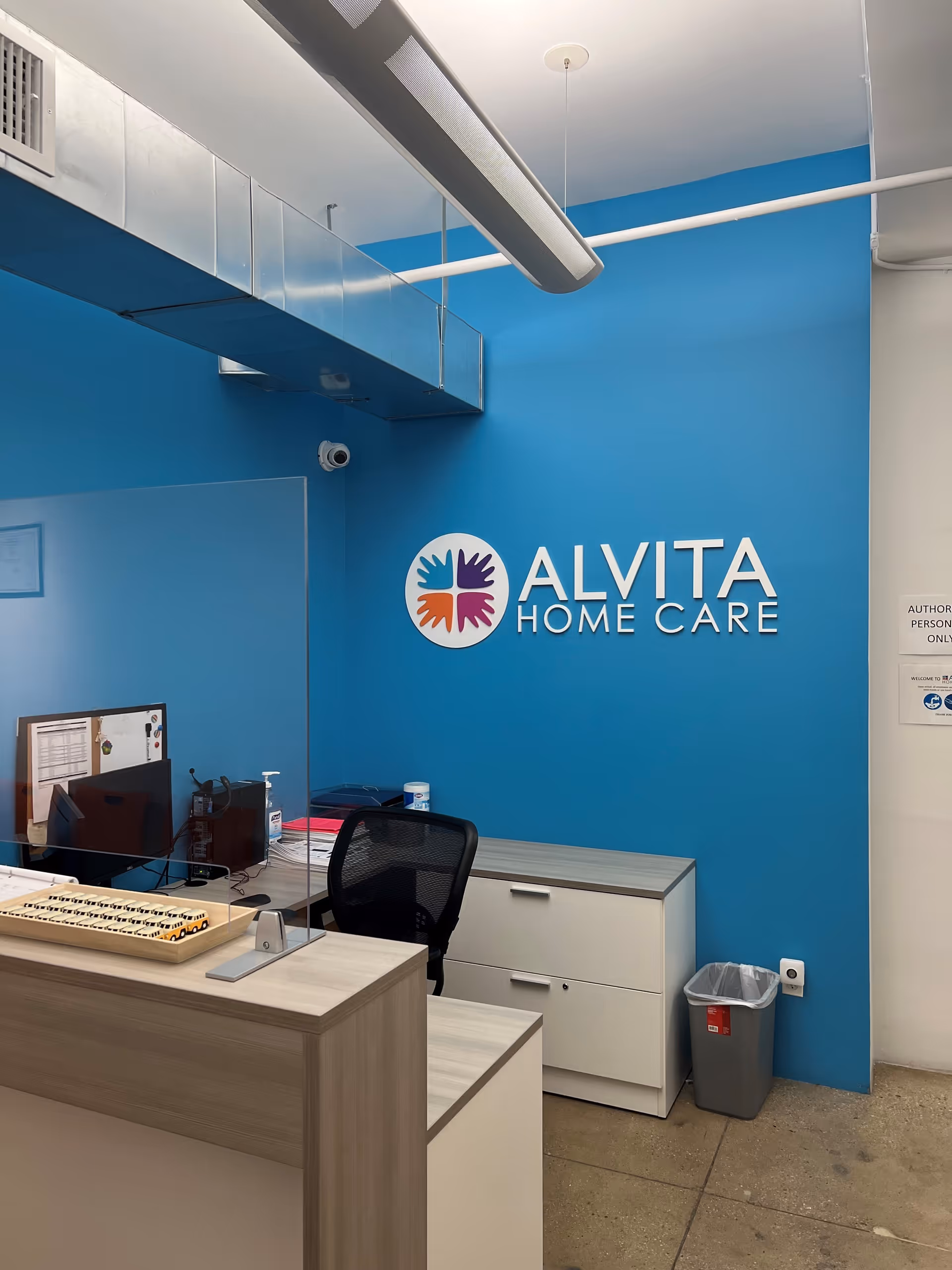 Reception desk inside a blue-walled Alvita Home Care office with logo