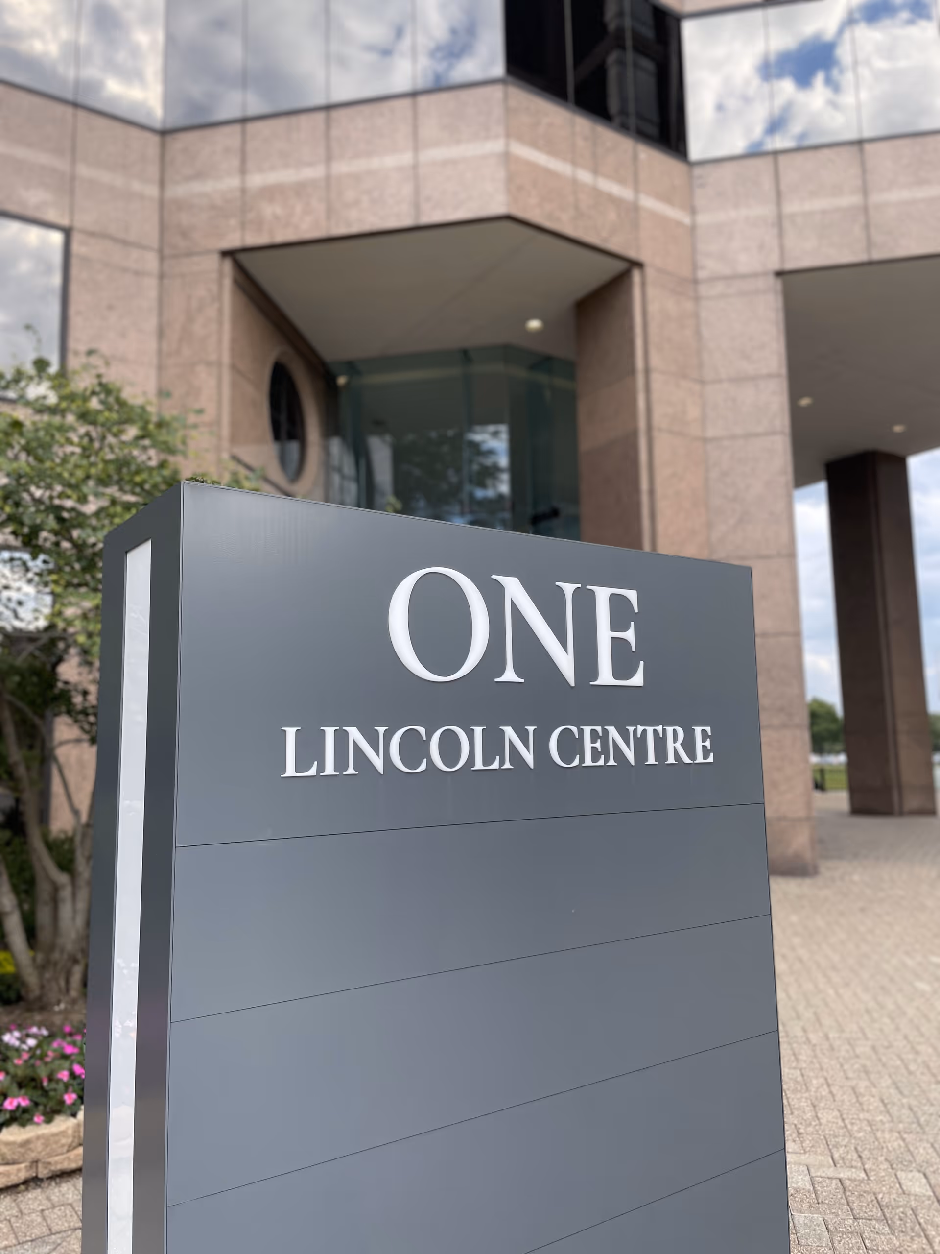 Modern building entrance with large sign reading ONE LINCOLN CENTRE