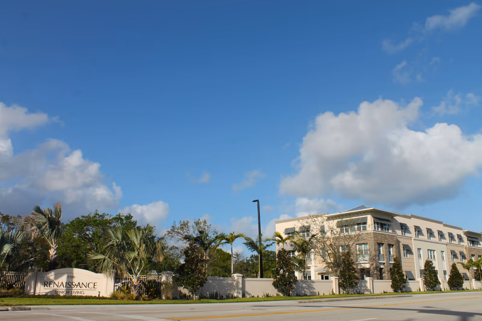 Exterior view of the Renaissance Senior Living building and entrance sign with palm trees under a blue sky.