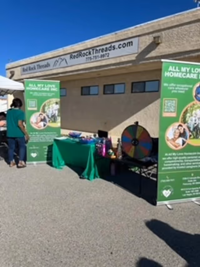 Outdoor promotional setup for All My Love Home Care with banners and a wheel game.