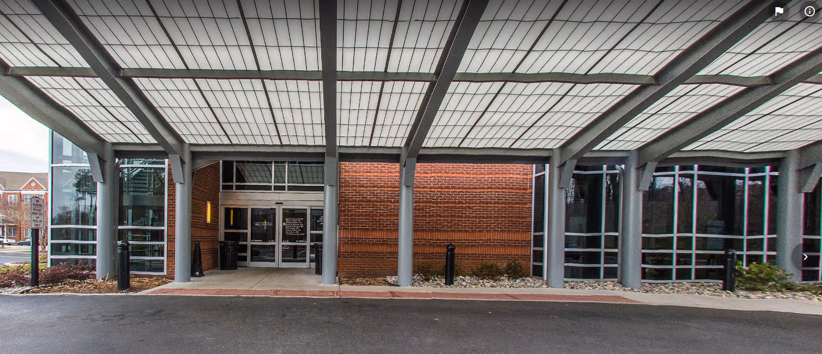 Exterior view of a medical center entrance with glass doors under a covered canopy.