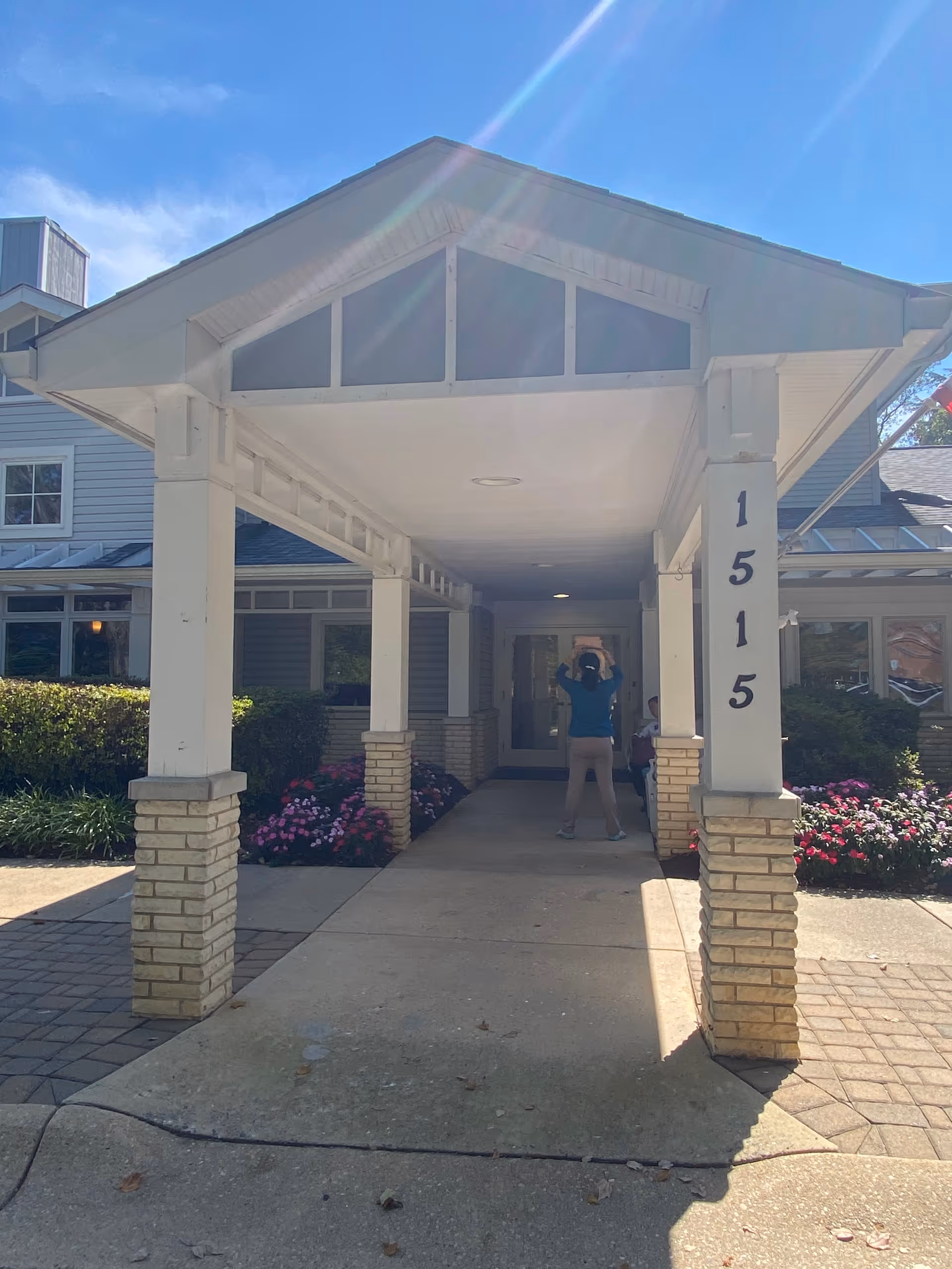 Covered entrance to Raphael House senior living facility with a person standing in the walkway.