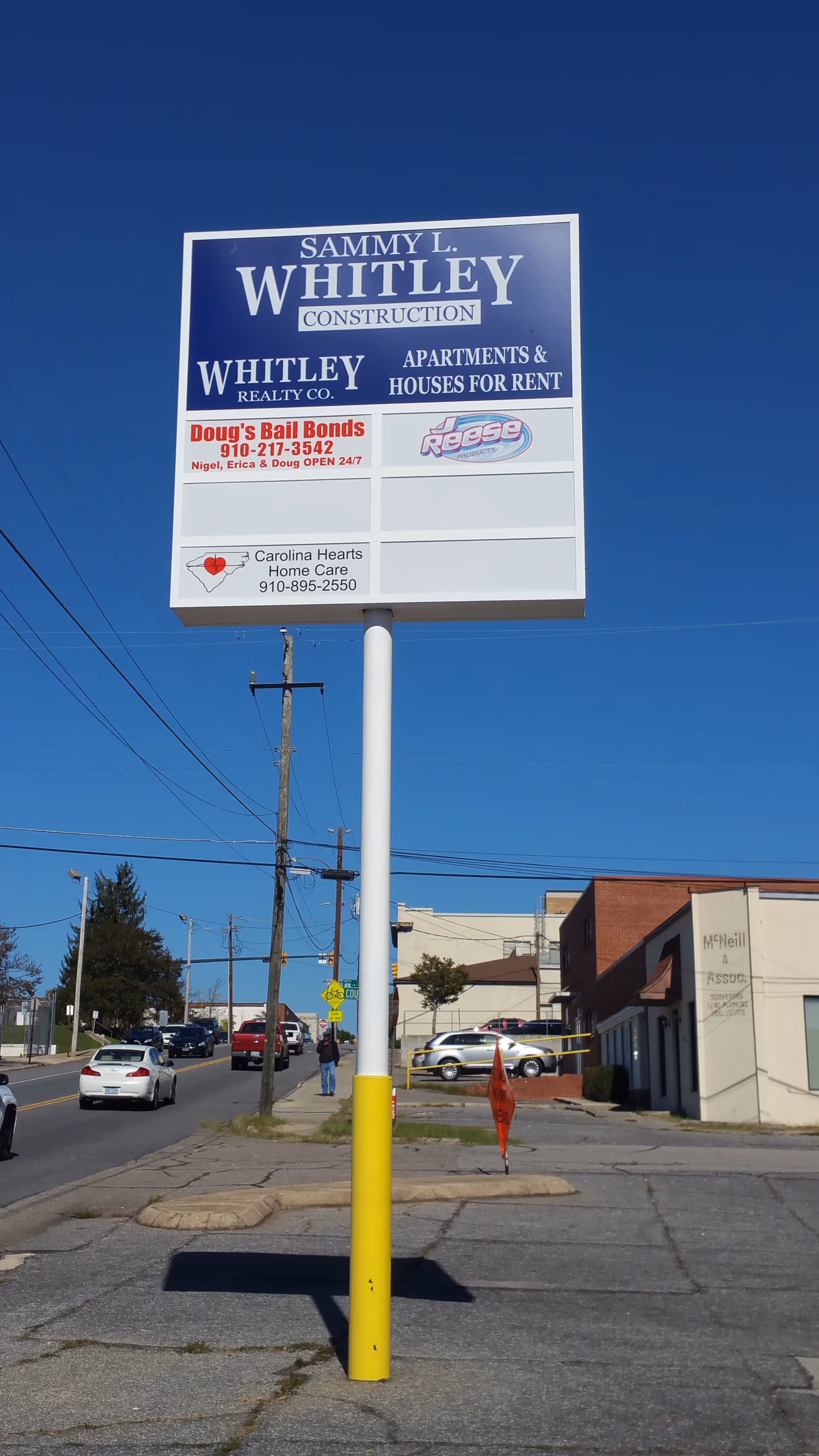Tall roadside sign for Carolina Hearts Home Care on a pole beside a building.