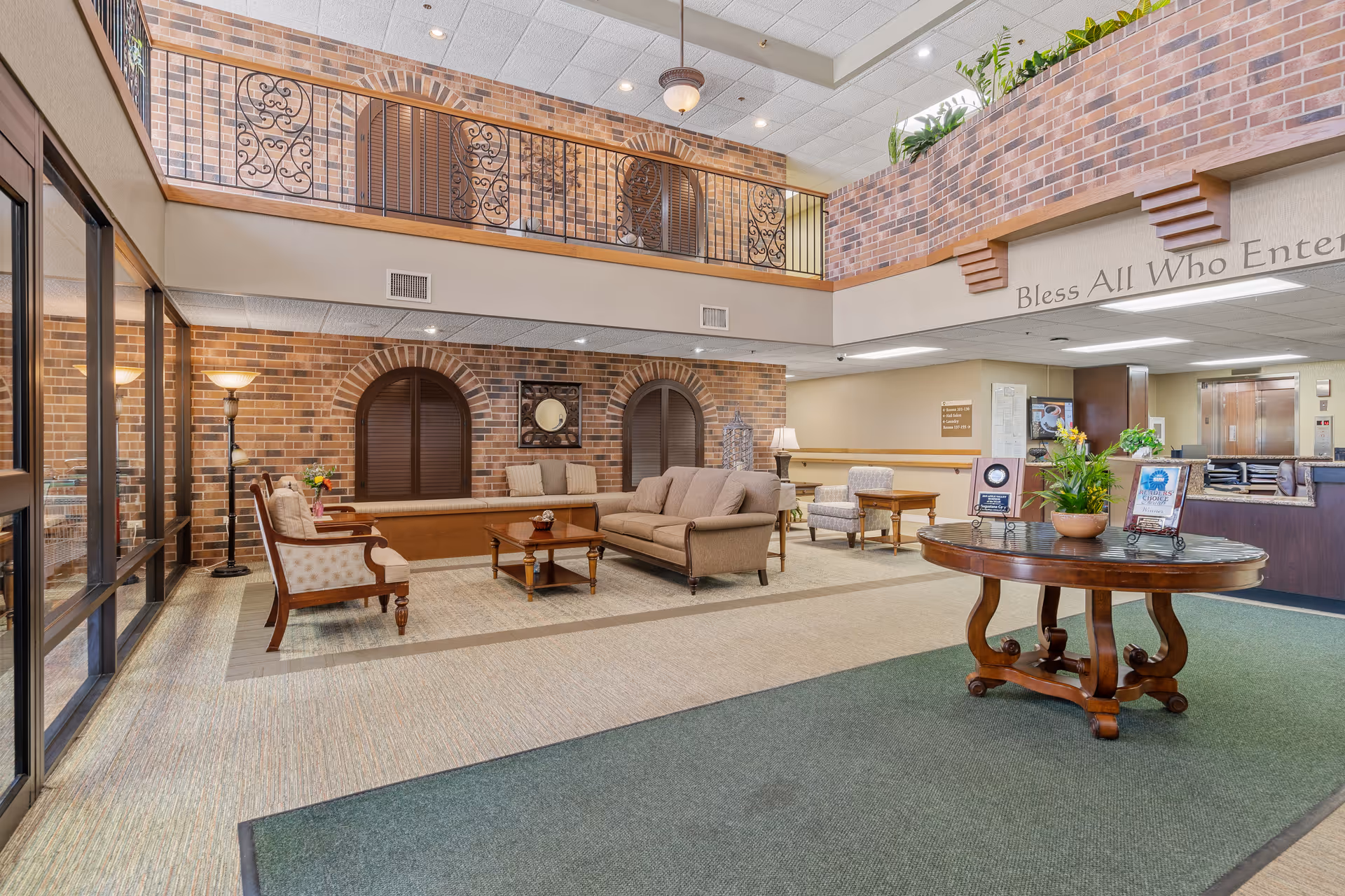 Senior living facility lobby with brick walls, seating area, and a second-floor balcony.
