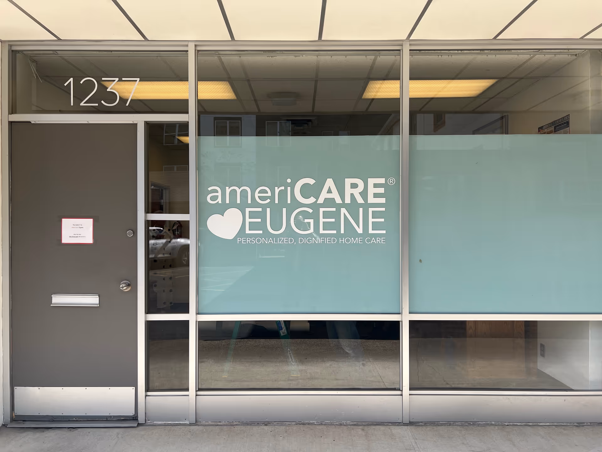 Storefront of AmeriCARE Eugene with glass windows and a door, address 1237.