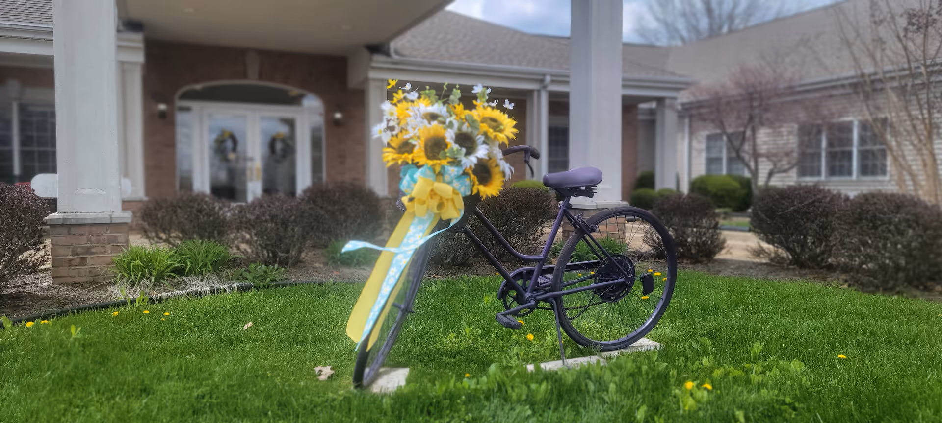 Front exterior of Paragon of Madisonville featuring a flower-decorated bicycle on the lawn.