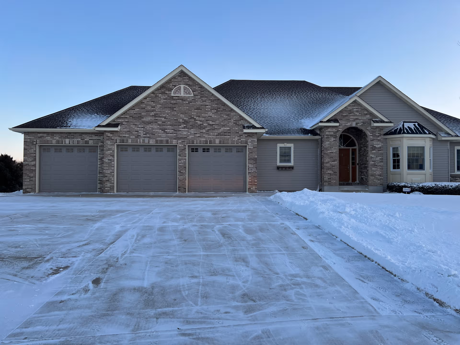 Wide view of a snow-covered senior living facility exterior with a brick front and garages.
