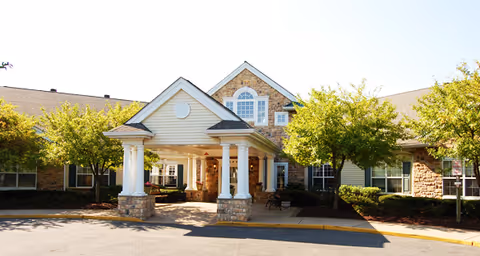 Exterior view of Brookdale Westampton entrance featuring stone-column portico and trees.