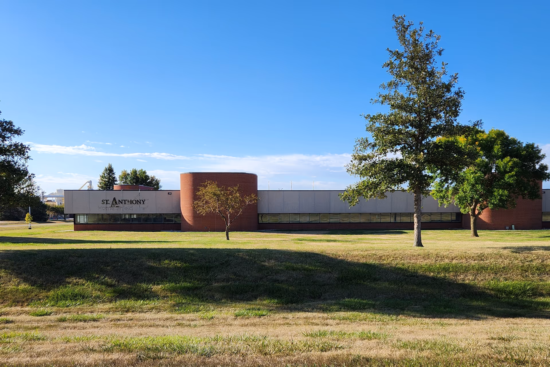 Exterior view of St. Anthony Office Building with brick curved center and trees on the lawn