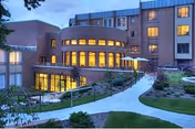 Exterior view of Marjorie P. Lee Retirement Community with illuminated curved glass entry.