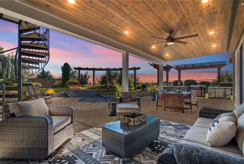 Covered outdoor patio with wicker furniture, dining area, and sunset sky.