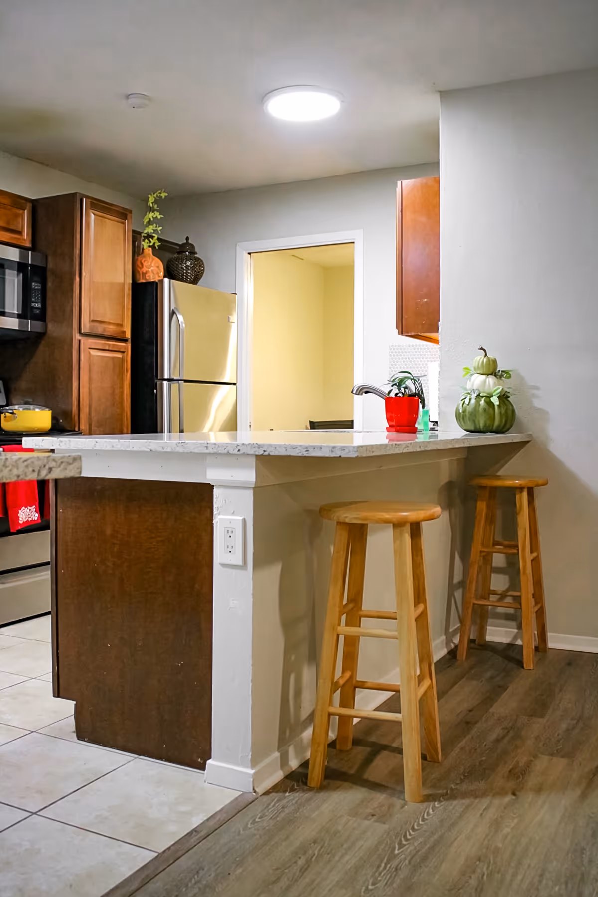 Kitchen area in a senior living home with island counter, stools, fridge, and cabinets.
