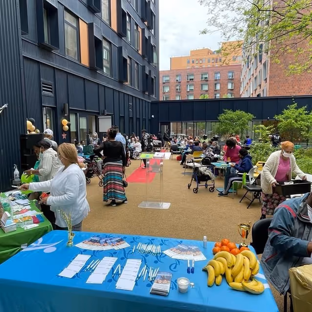 Outdoor courtyard at a senior living facility with people at tables.