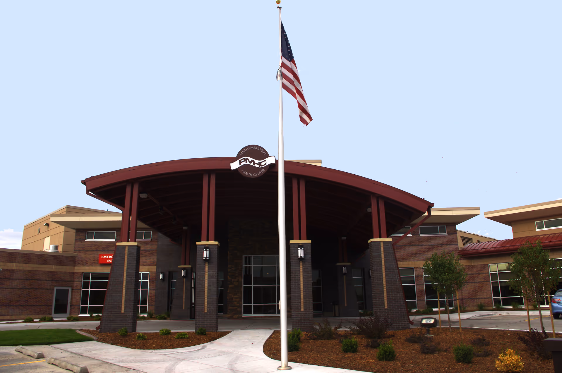 Front entrance of Phelps Memorial Health Center with flagpole and curved red canopy.