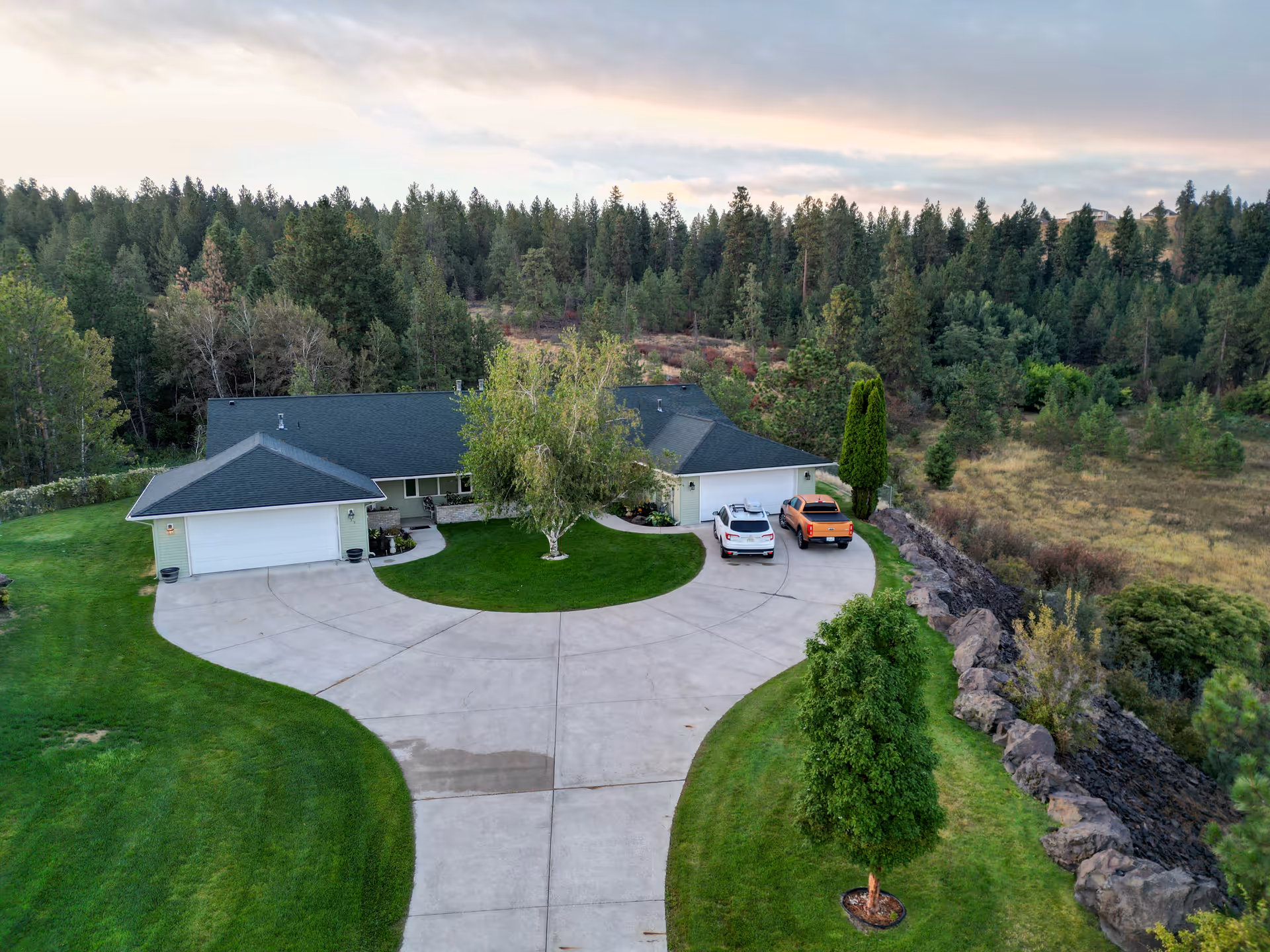 Exterior view of Olympus Living of Spokane Valley, with a circular driveway and green landscaping.