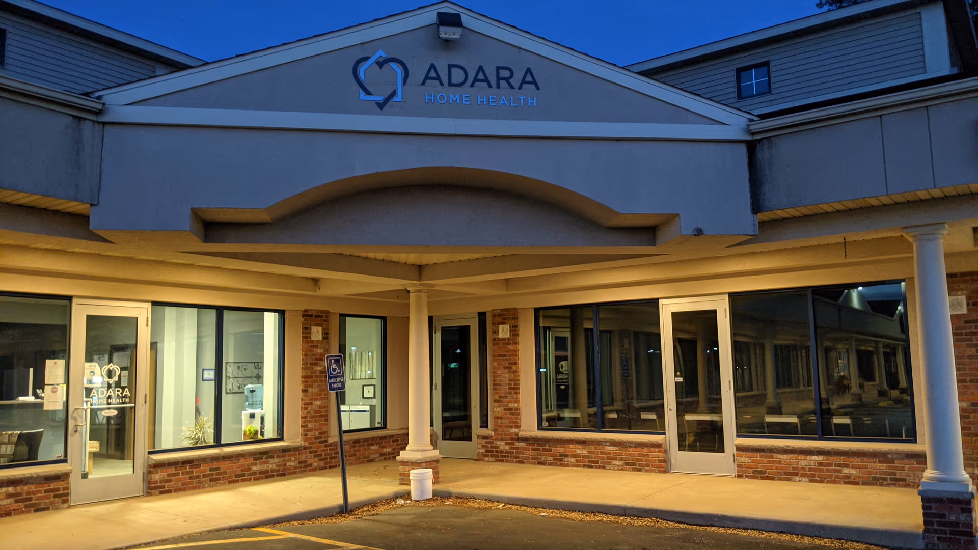 Storefront of Adara Home Health with glass doors, brick walls, and a covered entrance.