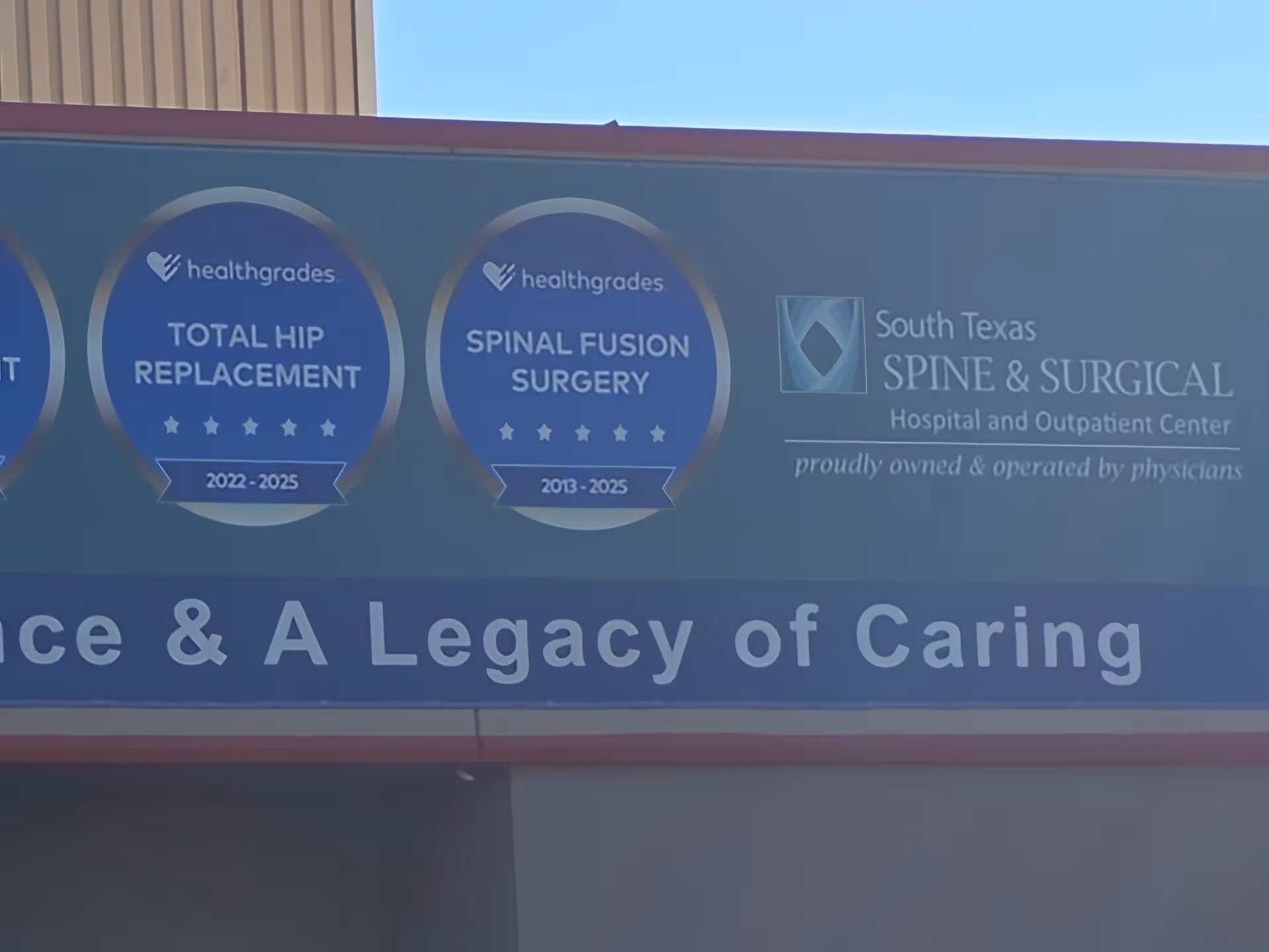 Blue exterior building sign displays Healthgrades awards and South Texas Spine & Surgical Hospital branding.